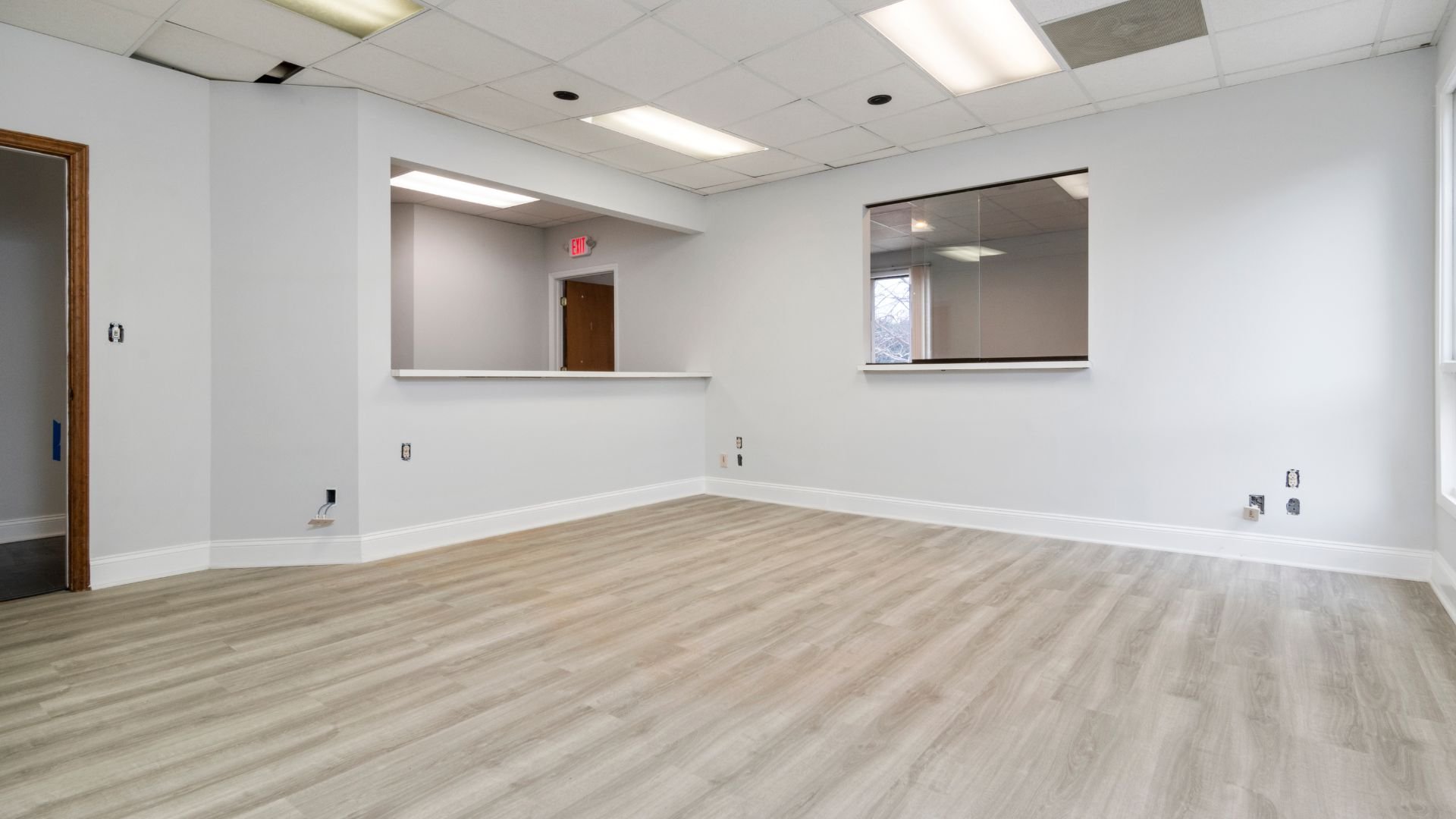 Empty white office room with wood floor and reception window