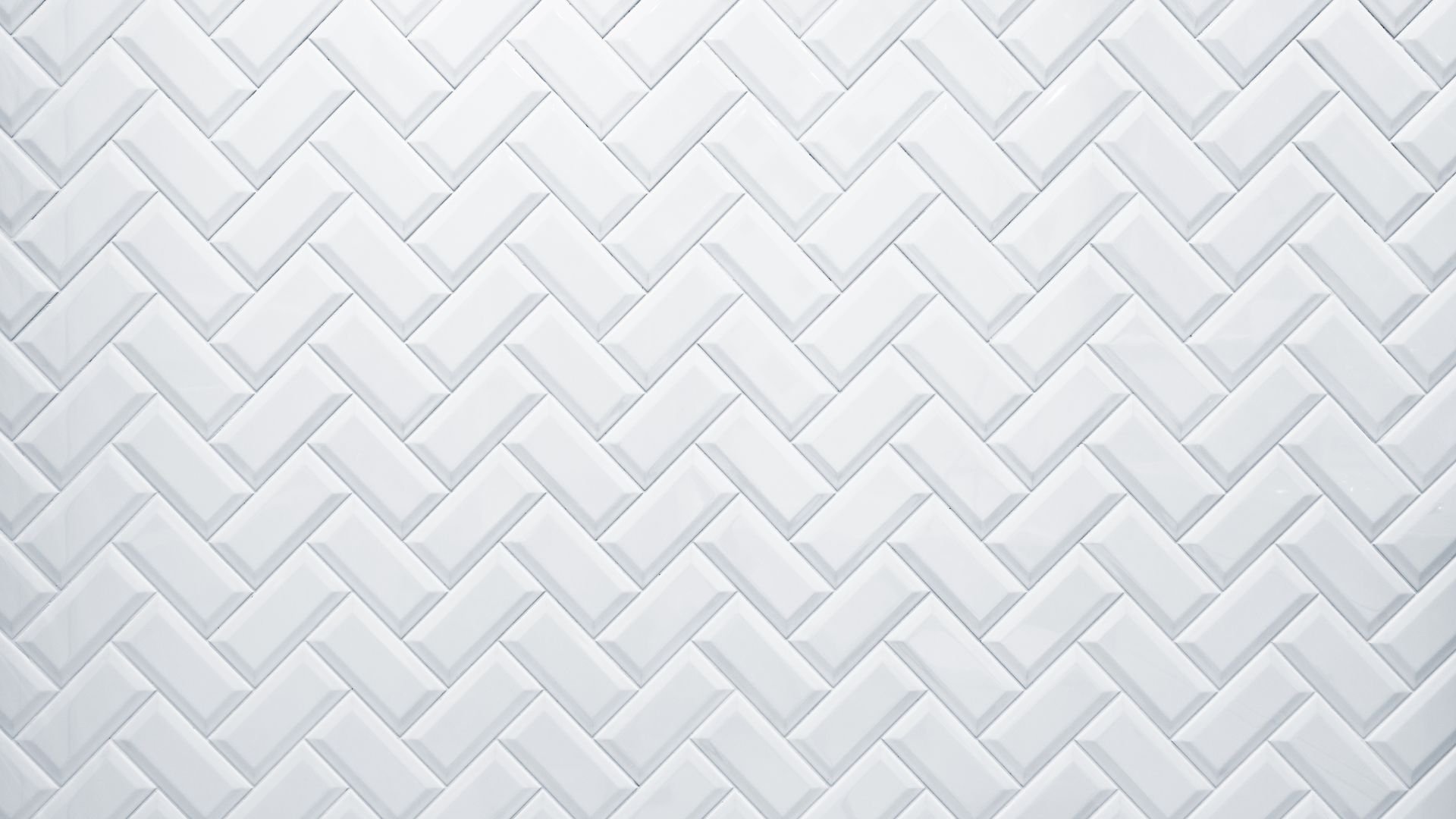 White ceramic subway tiles arranged in a herringbone pattern