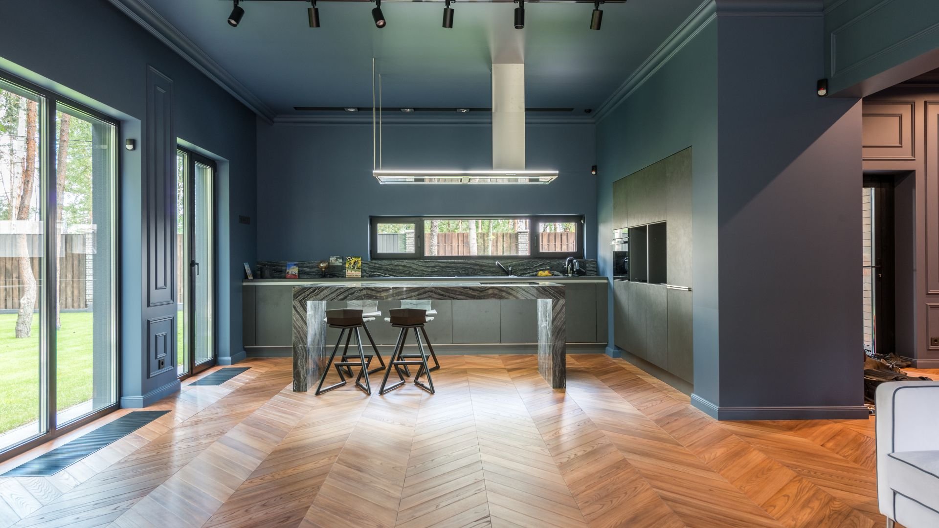 Modern kitchen with blue walls, herringbone floor, and large windows