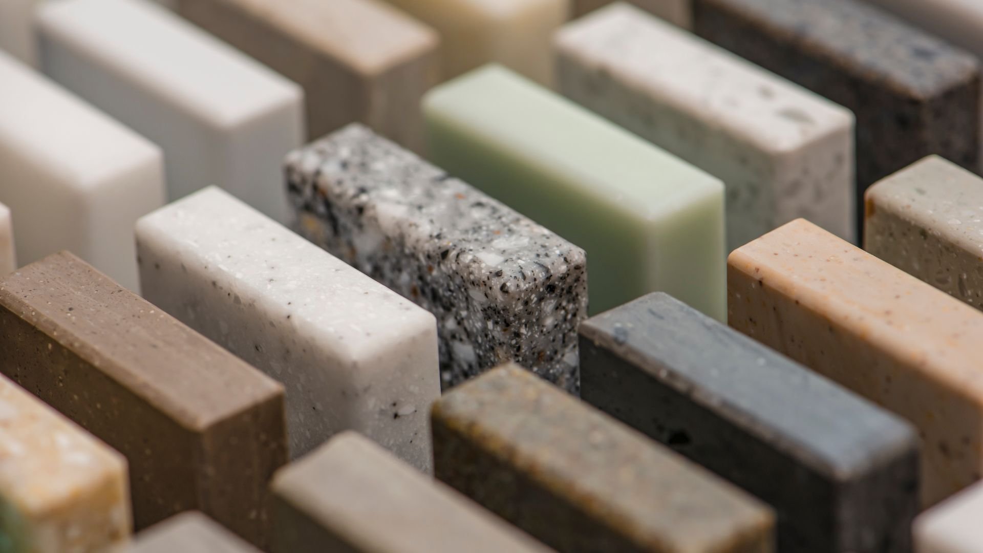 Close-up of various textured stone or quartz surface samples in neutral colors