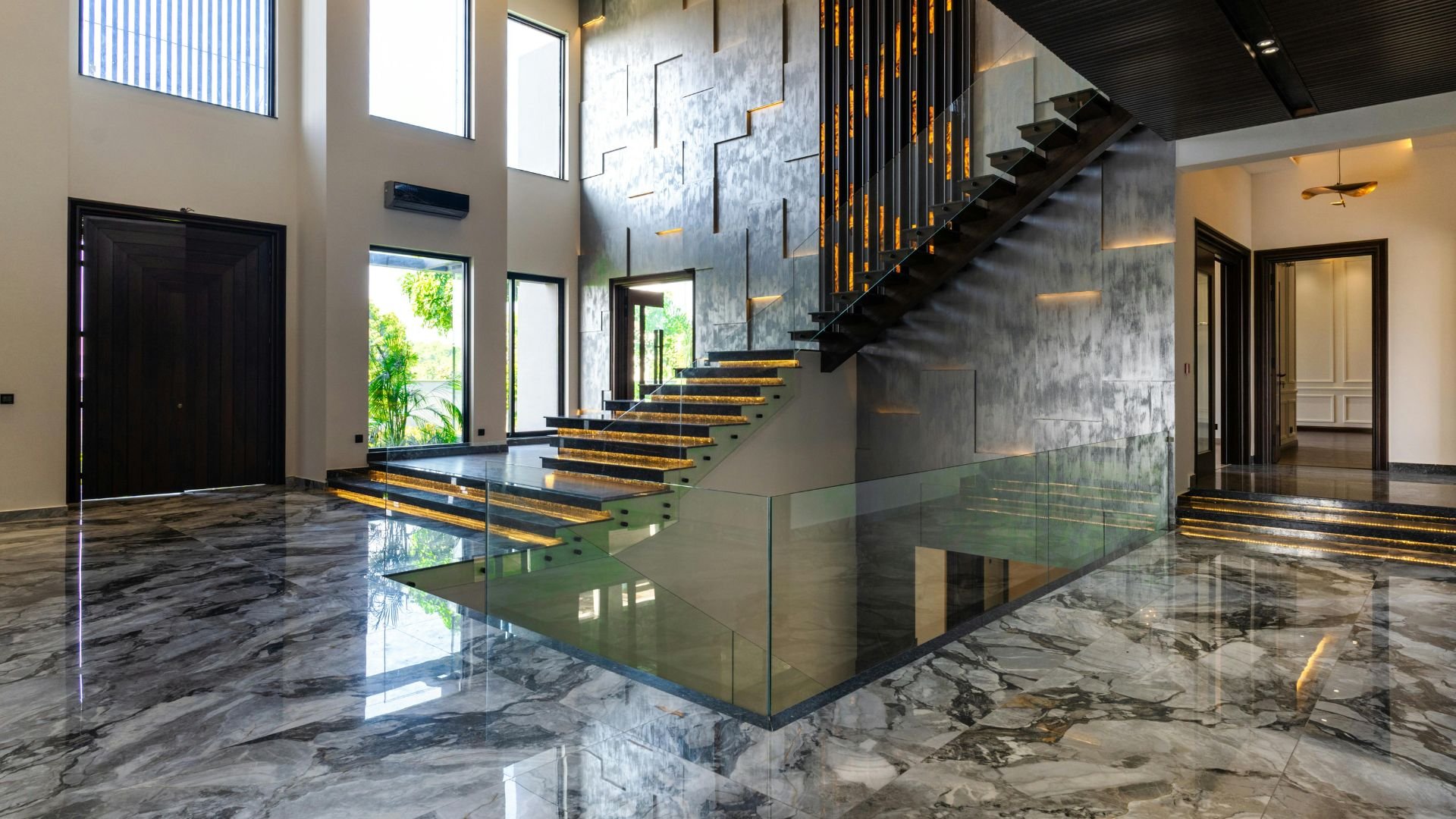 Modern interior with glass staircase, marble floors, and illuminated steps